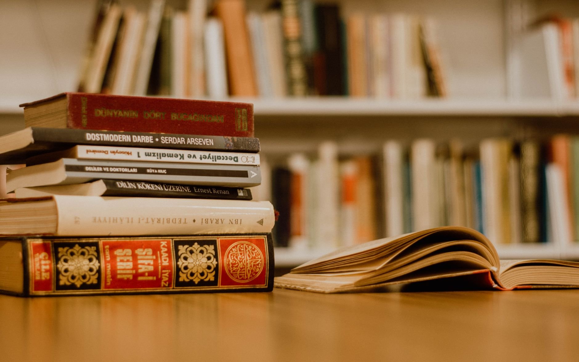 A warm-toned library scene with stacked books on a wooden table